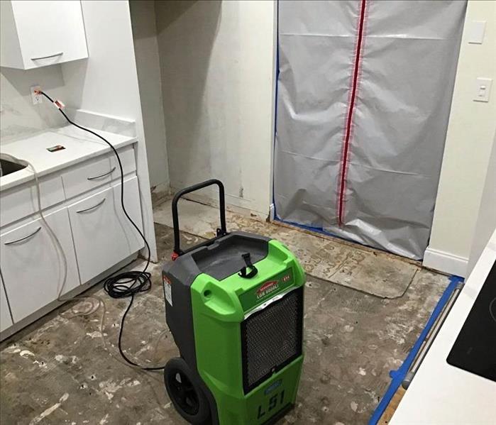 Dehumidifier standing on concrete floor in a kitchen.